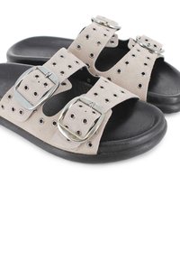 Sandalias de ante beige con dos correas anchas, hebillas plateadas y detalles perforados en la parte superior. Suela de goma texturizada negra.