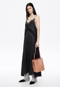 Mustvalge pitsäärisega satiinist maxi-kleit, millel on spagetirihmad, koos tekstuursete hõbedaste legginsitega, mustade terava ninaga korteritega ja helesinise käsitaskuga.