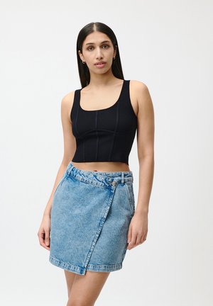 Svart cropped topp med tykke stropper og ribbet tekstur, parret med en lys blå, omslagsstil denimskjørt med knappelukking og frynsete kant.