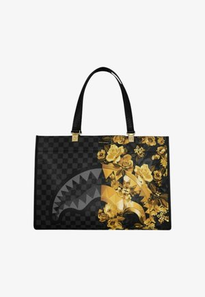 Bolso tote de cuadros negros con asas negras, con un diseño de boca de tiburón parcialmente superpuesto con patrones florales amarillos y dorados.