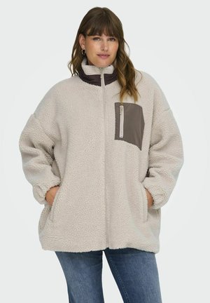 Fleecejacke in hellbeige mit lila Kragen und Brusttasche. Verfügt über Seitentaschen, lockere Passform und strukturierten Stoff. Reißverschlussverschluss.