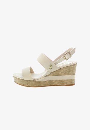 Beige wedge sandals with two wide straps and an ankle strap. Textured straw-woven platform with a smooth, light-colored footbed. Gold hardware accent.