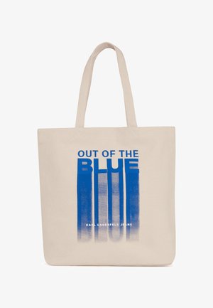 Platnena torba u bež boji s plavim natpisom "OUT OF THE BLUE" i vertikalnim uzorkom; sadrži čvrstu tkaninu i dvostruke ručke.