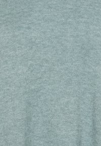 Maglione blu chiaro lavorato a maglia con una fine texture, caratterizzato da un design a costine e fibre morbide, adatto per essere indossato a strati in vari outfit.