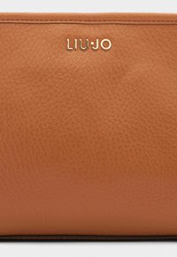 Bruin leren portemonnee met een gestructureerd oppervlak, voorzien van een gouden "LIU·JO" logo en gestikte randen, wat wijst op vakmanschap van hoge kwaliteit.