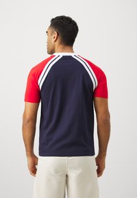 Camicia a maniche corte da uomo con maniche rosse, corpo blu navy e strisce bianche sulle spalle. Tessuto di cotone con una texture liscia e vestibilità casual.