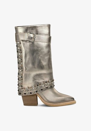 Stivale da cowboy argentato metallizzato con accenti di borchie, dettaglio con fibbia sul risvolto, punta appuntita e tacco in legno sovrapposto.