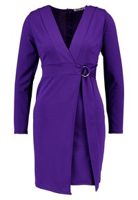 Robe violette en tissu lisse, dotée de manches longues, d'un design noué et d'un accent métallique circulaire à la taille. Fermeture éclair dans le dos.