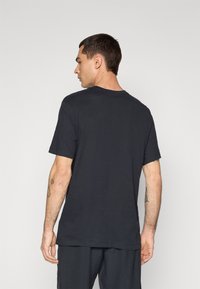 T-shirt in cotone nero con colletto rotondo, maniche corte e vestibilità comoda, caratterizzata da un design semplice senza decorazioni o fantasie.