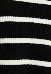 Black and white striped fabric with a ribbed texture. Alternating thick black and thin white stripes, showcasing a soft, warm material.