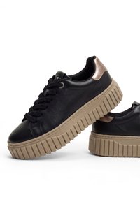 Schwarze Ledersneaker mit dicken beigen profilierten Sohlen und metallischen roségoldenen Fersenakzenten, aus seitlichen Blickwinkeln auf weißem Hintergrund gezeigt.