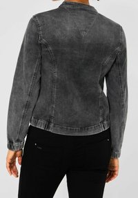 Chaqueta vaquera en gris desvaído, con cuello mandarín, ajuste ceñido y puños elásticos. Detalle de costuras a lo largo de las costuras y el yugo trasero.