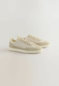 Zapatillas beige con parte superior de malla y acentos de ante, que cuentan con una puntera redonda, cordones planos y una suela de goma texturizada.