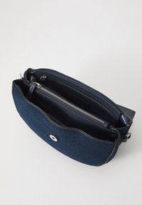Crossbody-väska i denim i mörkblått med en slank profil, mjuk textur, svarta läderdetaljer och ett blixtlåsfack.