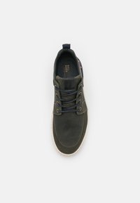 Dark green sneaker with textured fabric, round toe, and contrasting laces. Features a black leather accent and light-colored sole.