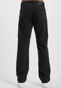 Black denim jeans with a relaxed fit, featuring two back pockets, a leather patch at the waist, and straight leg design. Smooth texture.