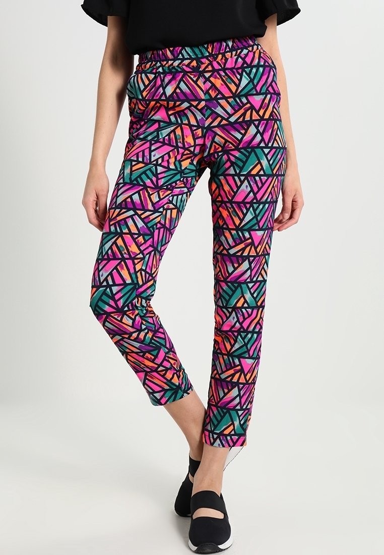 Barevné legíny s geometrickým vzorem v růžové, oranžové a tyrkysové barvě na černém pozadí. Elastický pás a zúžený střih nohavic.