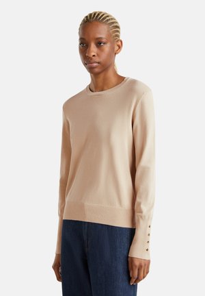 Beige gebreide trui met een ronde halslijn, lange mouwen, ribgebreide zoom en knoopdetails op de mouwboorden. Zachte textuur en aansluitend ontwerp.