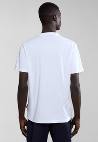 Tricou alb din bumbac, cu guler clasic tip crew și mâneci scurte, cu tiv drept și branding minimal pe lateral.