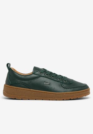 Dunkelgrüner Ledersneaker mit brauner Gummisohle, Schnürung vorne und kleinem Krokodillogo an der Seite, von der Außenseite betrachtet.