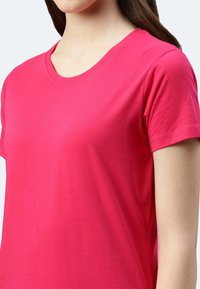 T-shirt in cotone di un brillante colore rosa, con collo rotondo e maniche corte. Texture liscia con una vestibilità morbida.