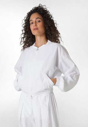 White bomber jacket with elastic cuffs, zip closure, and side pockets. Made of lightweight fabric, featuring a smooth texture and relaxed fit.
