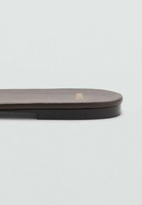 Intersuola marrone imbottita con una texture liscia, bordi arrotondati e una sottile suola nera. Presenta un discreto marchio dorato sul lato.