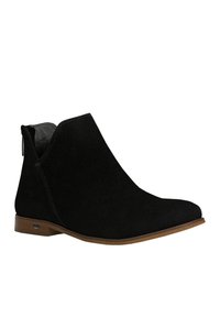 Stivaletto in suede nero con punta arrotondata e liscia, tacco leggero e design con tagli laterali. Suola marrone chiaro con dettaglio del logo.