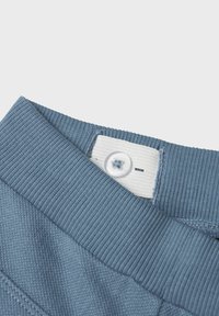 Niebieski prążkowany pas z białą metką i przezroczystym guzikiem. Posiada teksturowany wzór w diamenty na materiale.