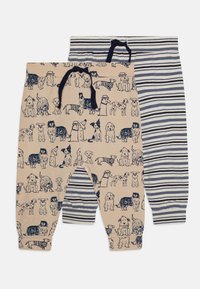 Två par barnbyxor: en med beige bakgrund som har hundillustrationer, den andra med marinblå och vita horisontella ränder.