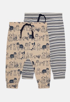 Två par barnbyxor: en med beige bakgrund som har hundillustrationer, den andra med marinblå och vita horisontella ränder.