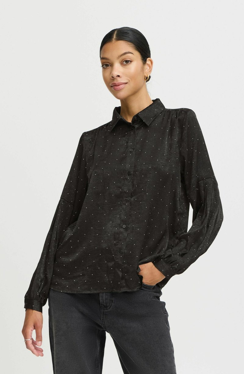 Must mustavalge täppidega must nööpidega shirt, mis on valmistatud pehmest kangast, pikad varrukad ja kerge lõige. Kombineeritud tumedate teksadega.