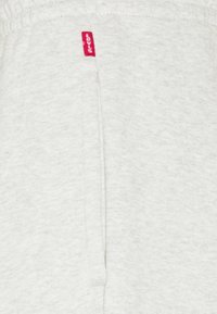 Lichtgrijze sweatshirt met een zachte textuur, met een naad in het midden en een rood Levi's label nabij de bovenrand.