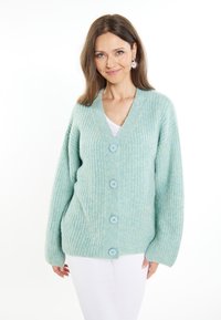 Cardigan lavorato a maglia di colore blu chiaro con scollo a V, cinque grandi bottoni e maniche lunghe. Presenta una texture a costine e una vestibilità rilassata.