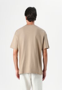 Beige bomulds t-shirt med korte ærmer, afslappet pasform og rund halsudskæring, med et enkelt design uden synlige mønstre eller logoer.