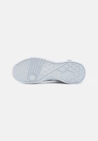 Suola di sneaker bianca con un pattern testurizzato che presenta forme esagonali, scanalature e accenti circolari per grip e trazione.