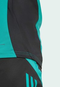 Träningsshorts i en kombination av teal och svart färg, med en slät textur, kontrasterande sidopaneler och synliga sömmar.