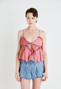 Top a canotta fiorita rosa aderente con orlo arricciato, spalline sottili regolabili. Indossato con pantaloni corti in denim a vita alta.