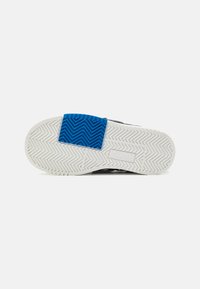 Suola di scarpa sportiva nera con un motivo a zigzag bianco, con un accento in gomma blu sul tallone per una maggiore presa e durabilità.