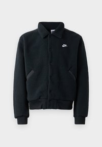 Črna flis jakna z gumbom, rebrastimi manšeti in pasom. Ima majhen bel Nike logotip na levem prsnem delu in stranske žepe.