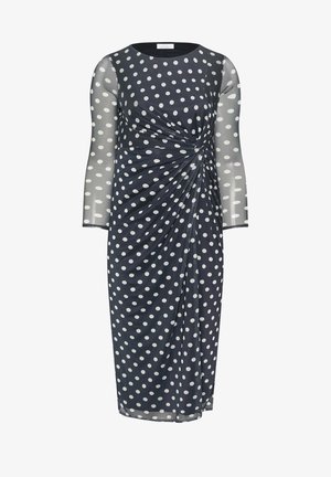Laivastonsininen polvimittainen mekko, jossa on valkoisia pilkkuja, läpikuultavat pitkät hihat ja vyötäröllä kerrostettu käänne.