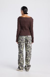 Top marrón de manga larga con textura acanalada, combinado con pantalones holgados de camuflaje verde. La parte superior presenta un escote caído.