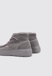 Botas de tobillo de ante gris con forro de forro polar, cordones rosas y costuras decorativas a lo largo de los lados. Suela de goma para agarre y durabilidad.