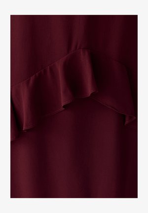 Dunkelburgunderfarbener Stoff mit einer horizontalen Rüsche, die eine wellige Textur über das Material erzeugt.