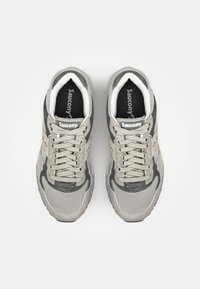 Chaussures de sport en mesh gris et en suède avec un design à lacets, présentant une surface texturée et le logo "Saucony" sur la languette.