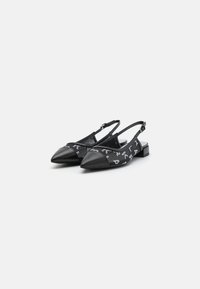 Chaussures à talons compensés noires avec un bout pointu, des accents en cuir et un tissu à motifs avec des détails blancs, sur un petit talon carré.