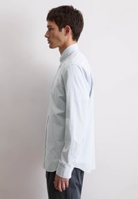 Lichtblauw geruite overhemd met lange mouwen gemaakt van katoen, met een knoopkraag, rechte snit en knoopmanchetten, gedragen met een donkere broek.
