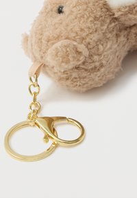 Brown plush keychain featuring a textured, fuzzy surface with a gold metal clip and ring attachment. Notable small ears and eyes.