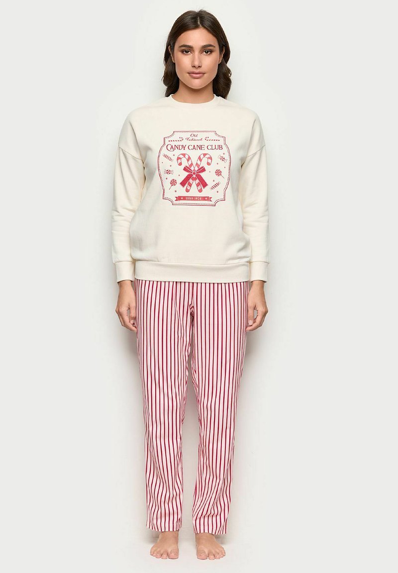 Felpa crema con grafica di un bastoncino di zucchero rosso, abbinata a pantaloni da pigiama a righe rosse e bianche. Vestibilità comoda e tessuto morbido.