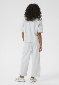 Outfit a righe blu chiaro e bianche composto da una maglietta a maniche corte e pantaloni larghi. Il materiale sembra leggero e confortevole.
